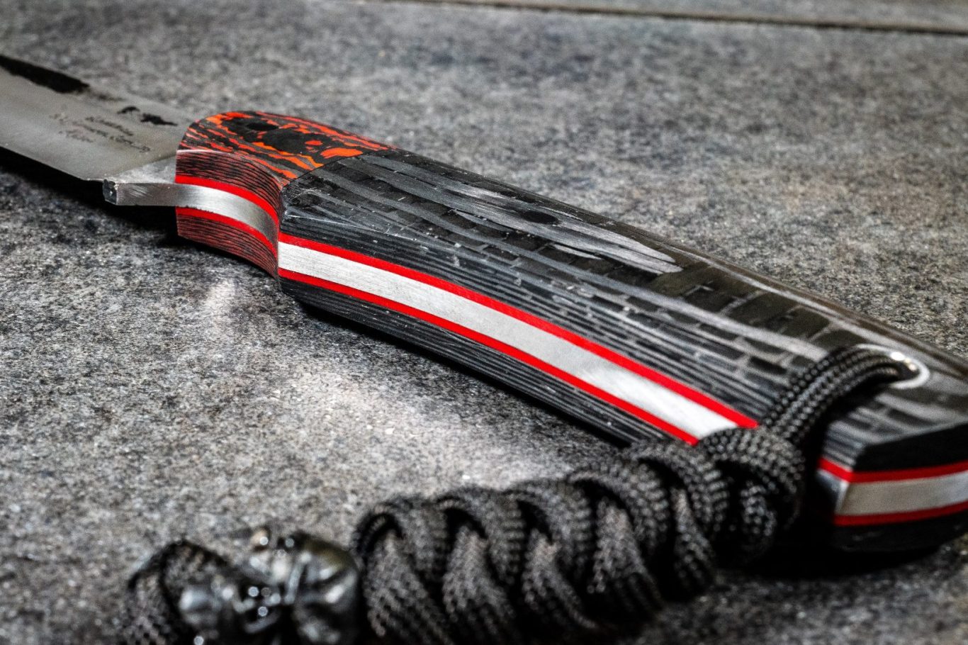 Griff aus verschieden farbigem Karbon Schwarzer Messergriff mit rot-weißen Akzenten und paracord-artigem Griffband.